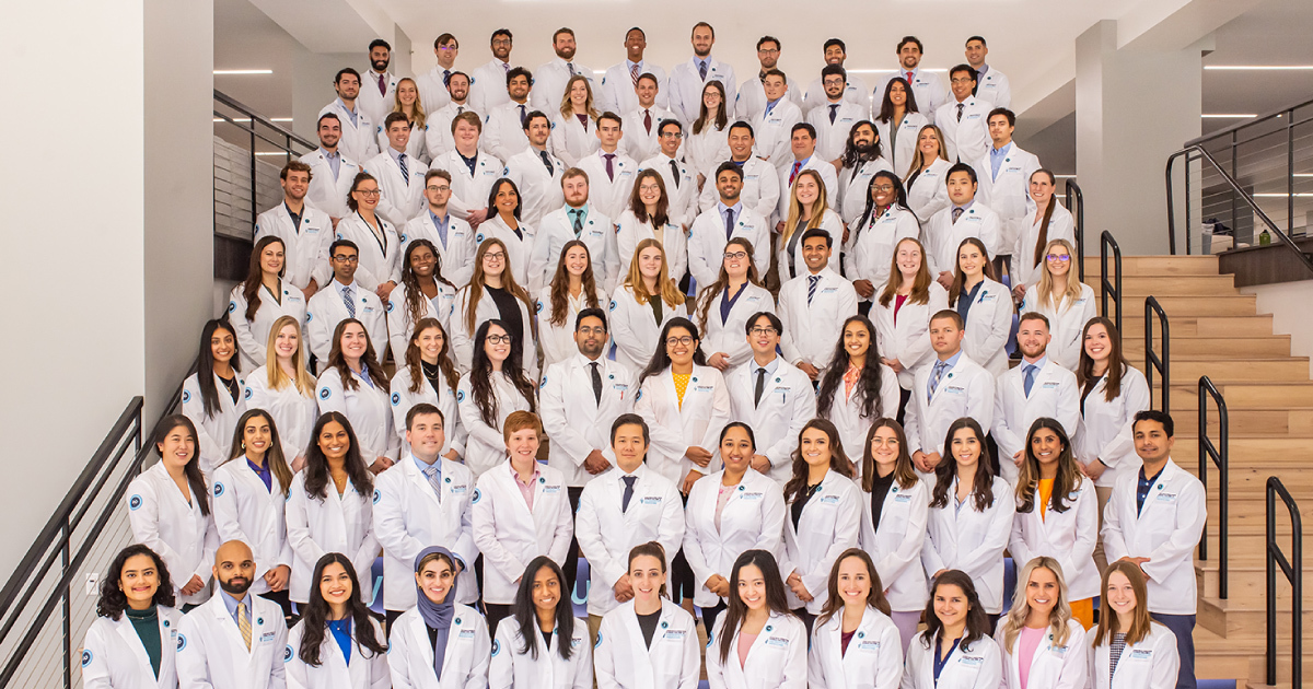 Med students in white coats standing on risers.