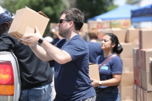 A man and woman in blue shirts load boxes into a pickup truck.