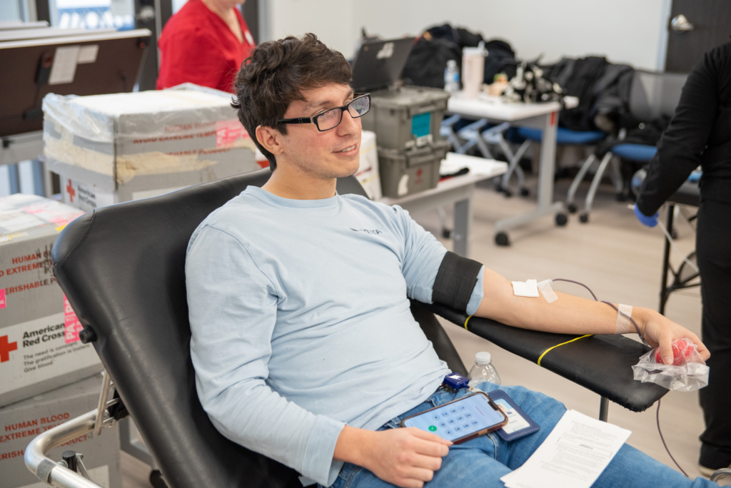 A student donates blood while looking into the middle distance.