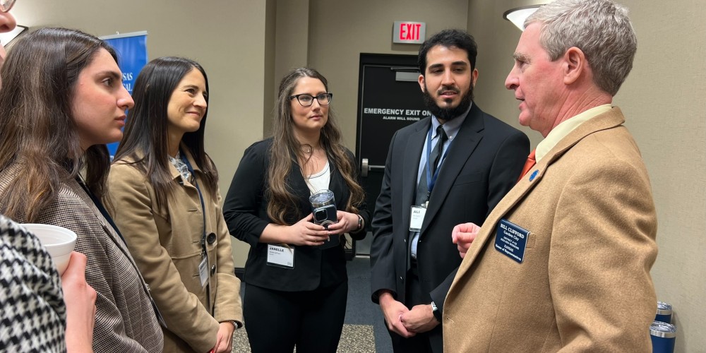 KansasCOM student doctors and Associate Dean Angie Carrick, DO speak with Representative Bill Clifford, MD, of Garden City, a seasoned ophthalmologist of three decades.