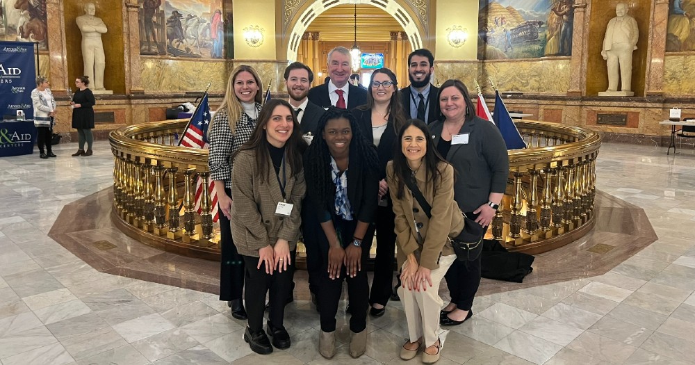 A group of student doctors and KHSC – KansasCOM staff and faculty gather in the Kansas Statehouse rotunda.