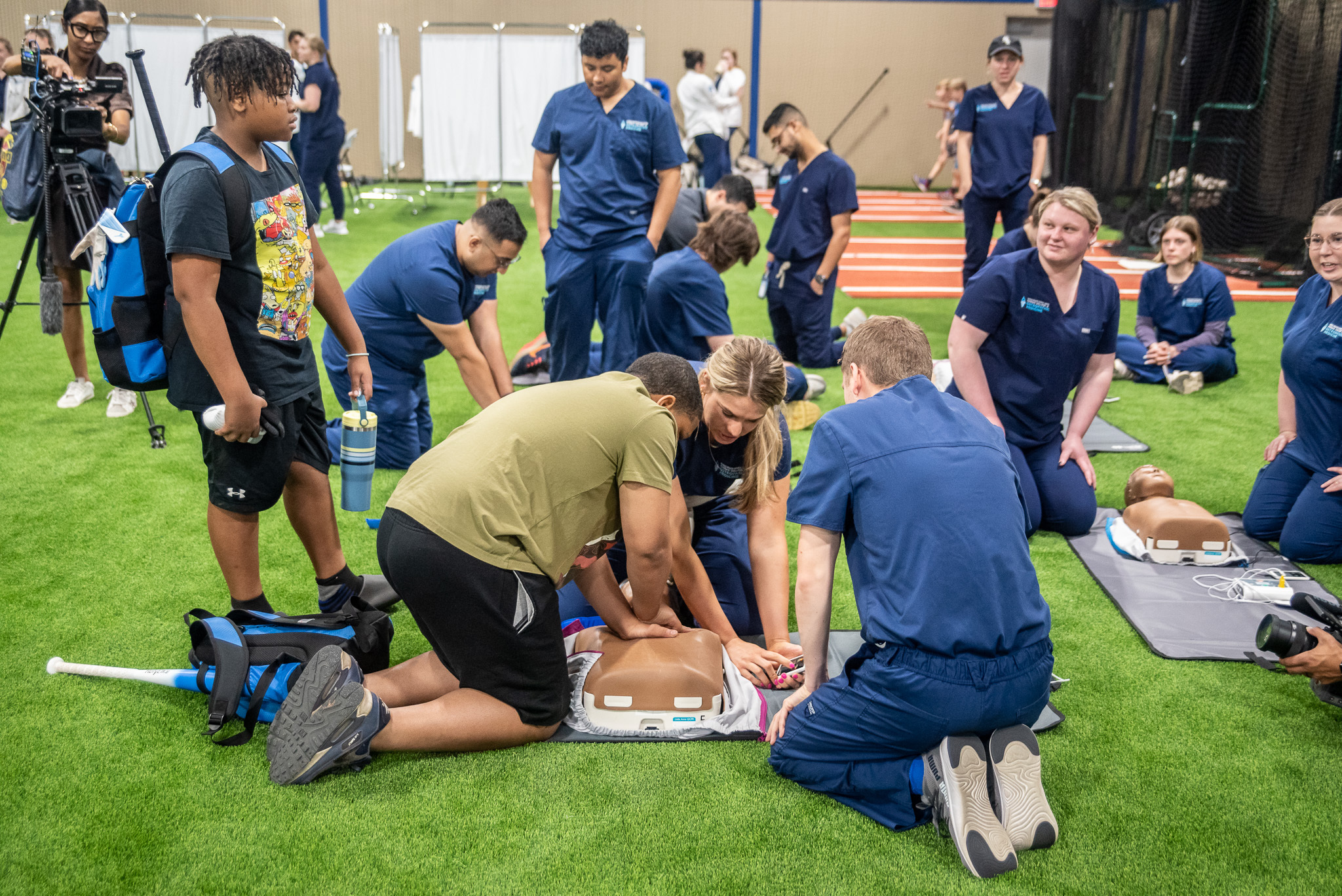 Students practice CPR on an indoor field during KansasCOM's DO Day of Service.