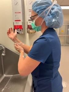 Woman in surgical garb washing hands.